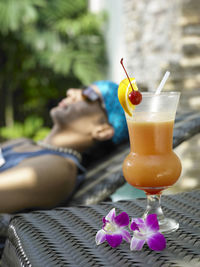 Close-up of drink with man relaxing on chair at poolside