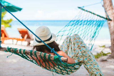 Midsection of man holding rope at beach against sky