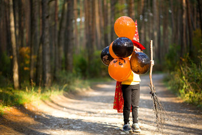 Rear view of man standing on road in forest