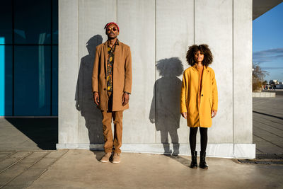 Full length of black african american couple in trendy vivid warm outfit standing with looking at camera on street