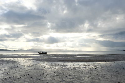 Side view of boats in calm sea against cloudy sky