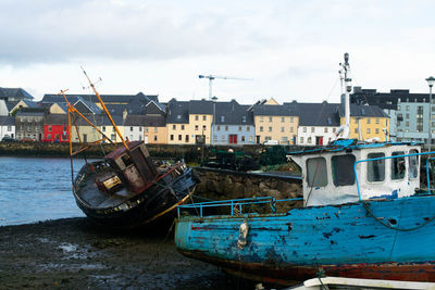 Boats moored on sea by buildings against sky