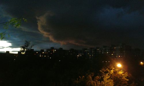 View of illuminated cityscape against cloudy sky