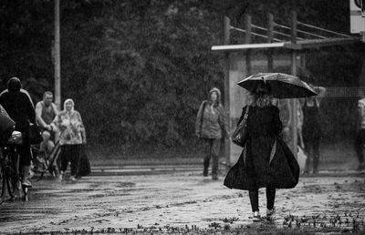 People walking on wet road during rainy season