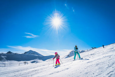 Mother teaching daughter how to ski, skiing down on a ski slope in andorra, pyrenees mountains