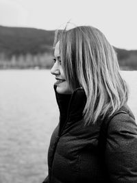 Smiling woman looking away while standing against sea and sky