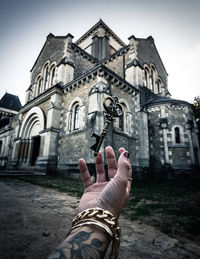 Low section of person holding cross against building