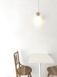 Empty chairs and table against wall in restaurant