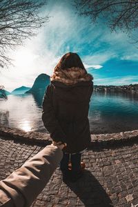 Woman holding cropped hand against sea