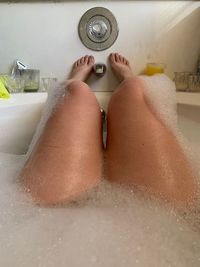 Low section of woman relaxing in bathroom