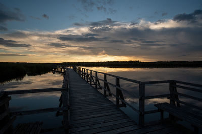 Pier over lake against sky during sunset