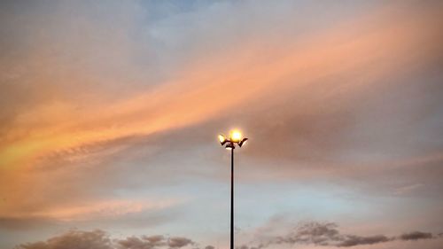 Low angle view of illuminated street light against sky at sunset