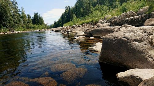 River flowing through rocks against sky