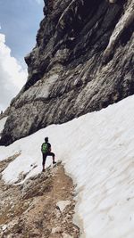 People on rock by mountain against sky