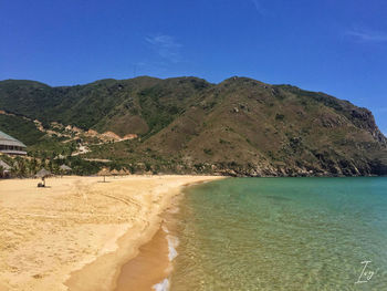 Scenic view of sea and mountains against blue sky