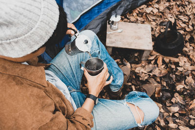 Man sitting pouring hot  espresso with italian moka coffee pot drinking in a forest on vacation