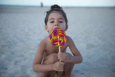 Full length of cute girl on beach with lollipop 