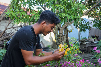 Side view of young man looking at flowering plants