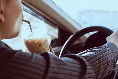Midsection of man drinking juice while driving car