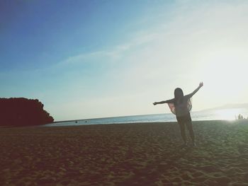 Woman standing on beach against sky during sunset