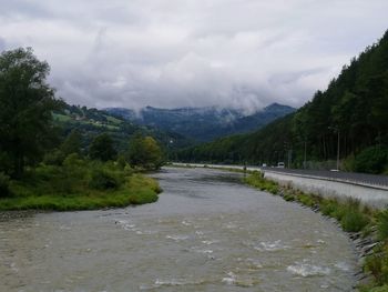 Scenic view of river by mountains against sky