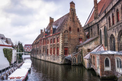 Snowy spring day in bruges canal looking over the old saint john's hospital. bruges, belgium