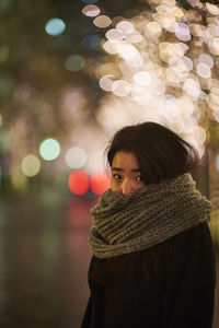 Portrait of woman with illuminated christmas lights during winter