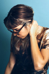 Close-up of young woman wearing sunglasses against blue background