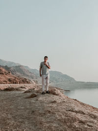 Young man standing on shore against sky