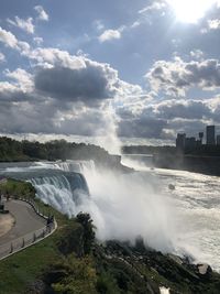 Scenic view of waterfall against sky in city