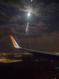 Airplane wing against sky during sunset