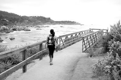 Rear view of woman walking on jetty against clear sky