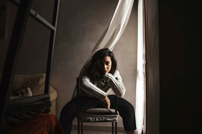 Portrait of woman sitting on chair at home