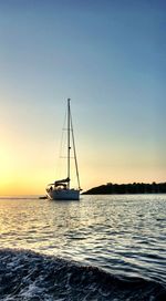 Sailboat sailing in sea at sunset