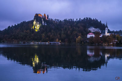 Reflection of trees and buildings in lake against sky