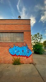 Low angle view of graffiti on wall against sky