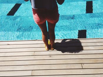 Low section of woman standing by swimming pool