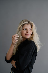 Portrait of young woman standing against gray background