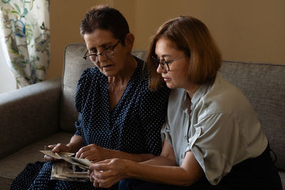 Mature daughter visits senior mother and watching family photo album