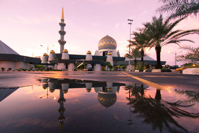 Reflection of palm trees and buildings against sky