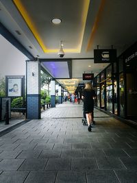 Rear view of woman walking in illuminated corridor