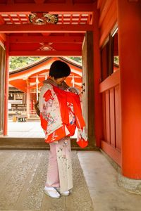 Full length of woman wearing kimono standing with baby girl in temple