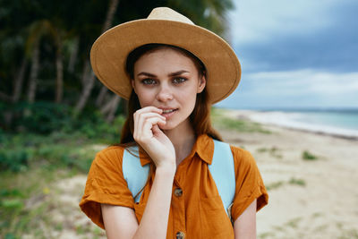 Portrait of young woman wearing hat standing on beach