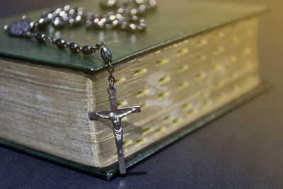 The cross over bible on wooden table with window light, and dark background. religion concept.