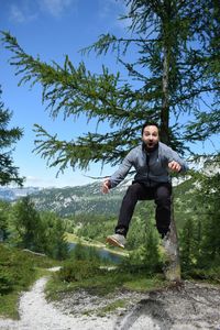 Portrait of mid adult man jumping on mountain against sky