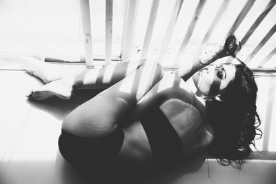 Seductive woman lying on floor by window