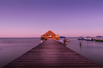 Pier over sea against sky at sunset