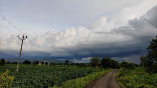 Road amidst field against sky