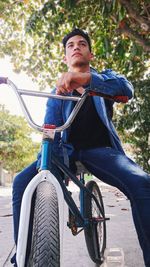 Low angle view of young man sitting on bicycle