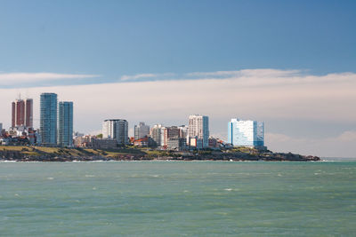 Sea by buildings against sky in city